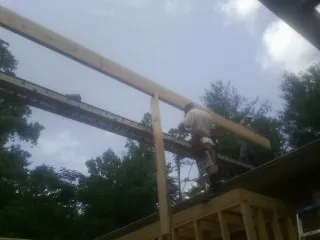 Carpenter setting a ridge beam over a new addition frame — Ice Dam Removal by Roofing Brothers in Conshohocken