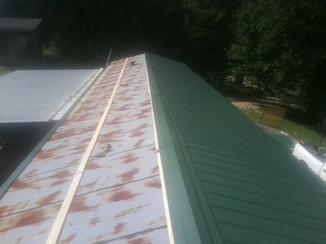 Old rusted panels beside newly installed green metal roofing — Wind Damage Roof Repair by Roofing Brothers in Conshohocken