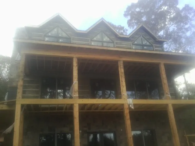 Dormers and porch framing on a large log home under construction — Roof Coating work by our crew in Conshohocken