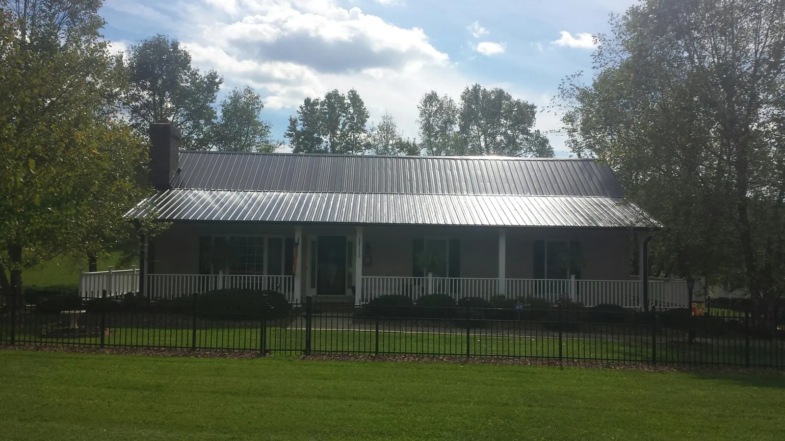 Gray metal roof on a brick ranch with a full width front porch — Gutter Guard Installation work by our crew in Conshohocken