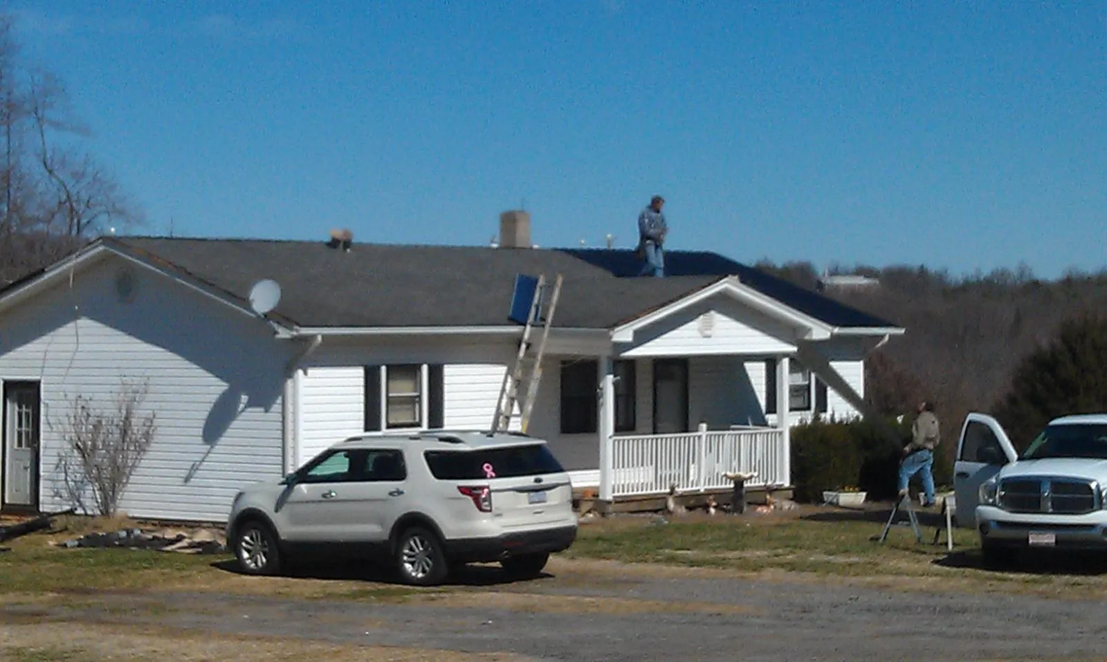 Roofers stripping shingles from a white ranch house roof in Conshohocken