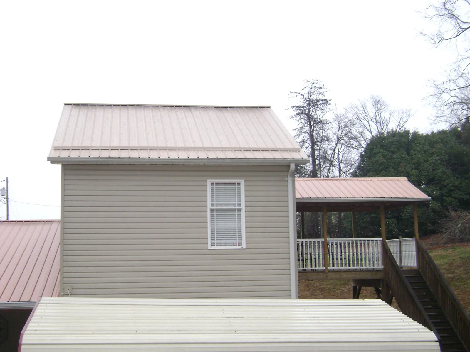 Tan metal roofs on a two story addition and attached porch, from a Roof Replacement job in Conshohocken