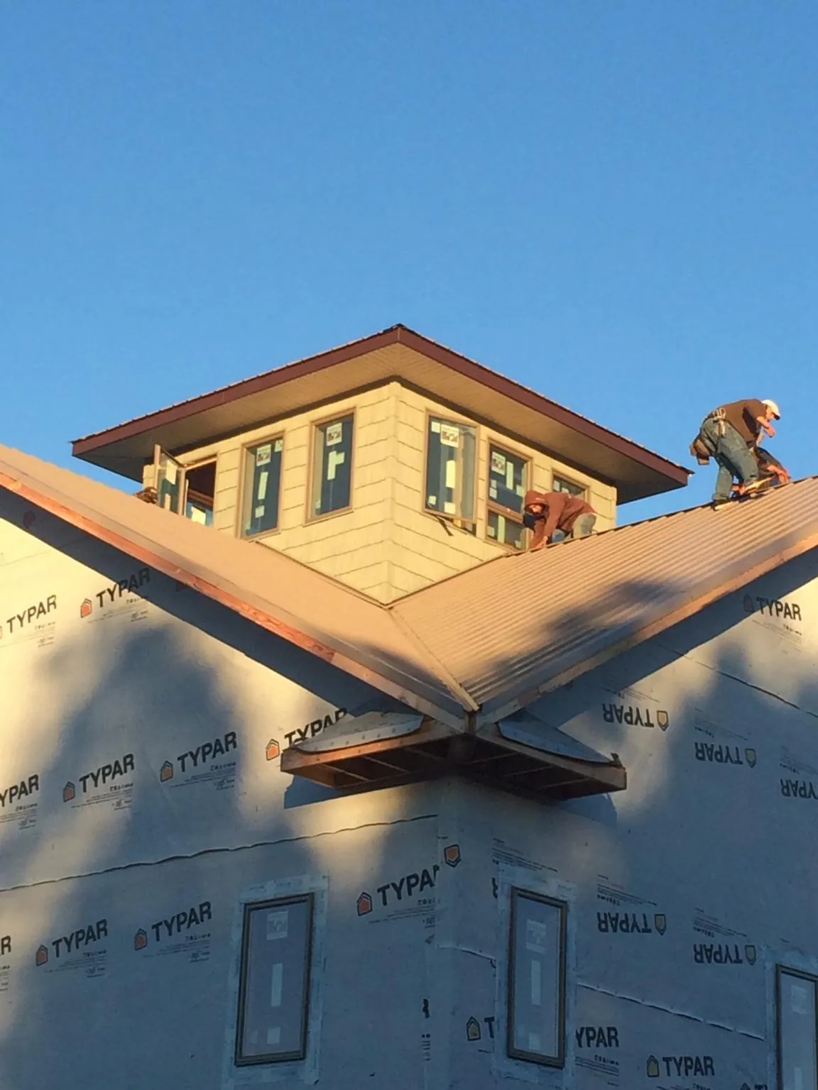 Roofers working around a rooftop cupola on a new metal roof at sunset — Roof Waterproofing in Conshohocken by Roofing Brothers